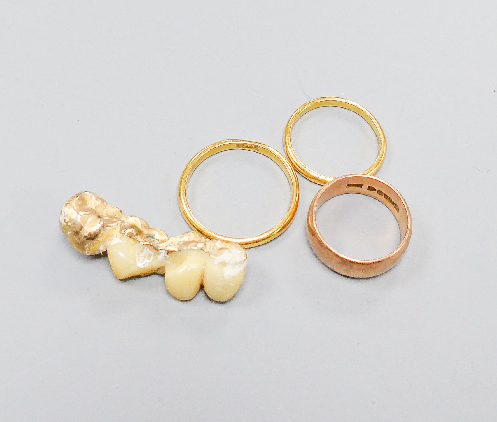 Two 22ct wedding rings, 5.7 grams, a 9ct rose gold wedding band 4.6 grams and four gold-mounted teeth.